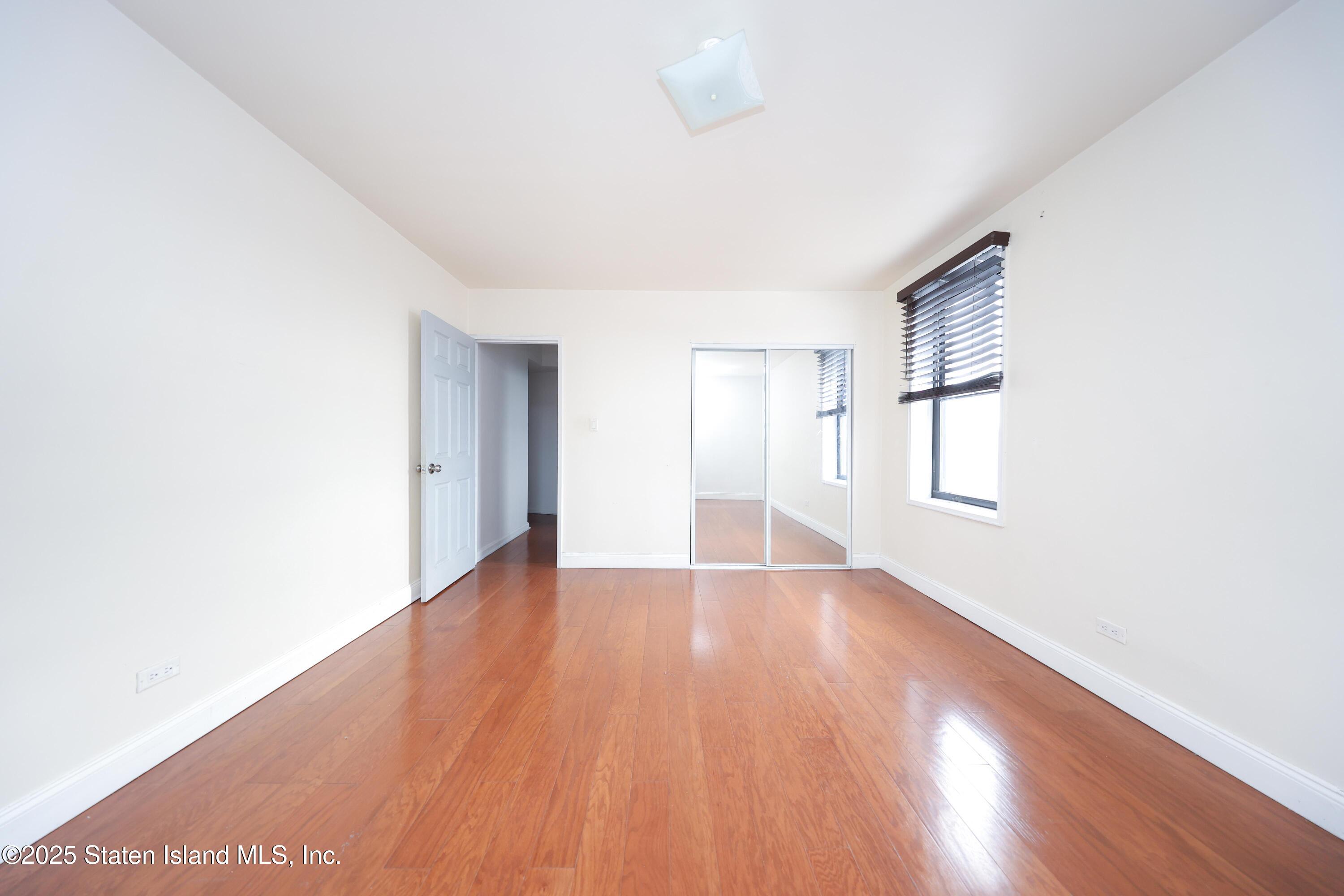 9040 Fort Hamilton Parkway, Unit 6C Brooklyn, NY 11209 - Photo 16 of 18 a view of an empty room with wooden floor and a window