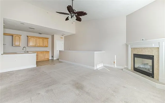 a view of a livingroom with a fireplace a ceiling fan and windows