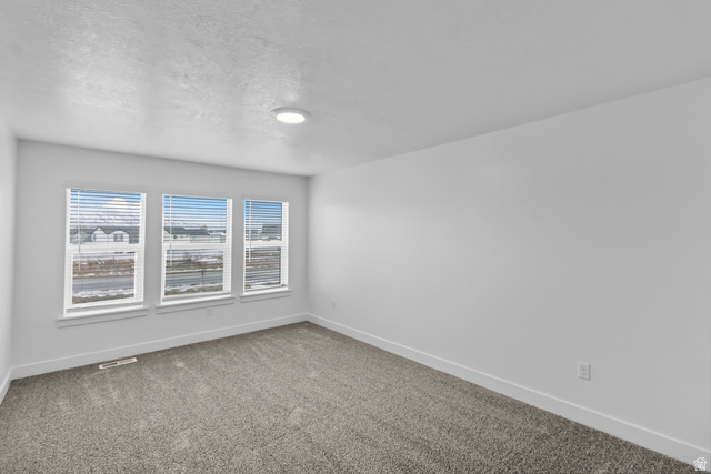 3014 South 265th Street West Logan, UT 84321 - Photo 20 of 25 Bright room featuring three windows with horizontal blinds, neutral-toned carpeting, white walls, and a flush-mount ceiling light