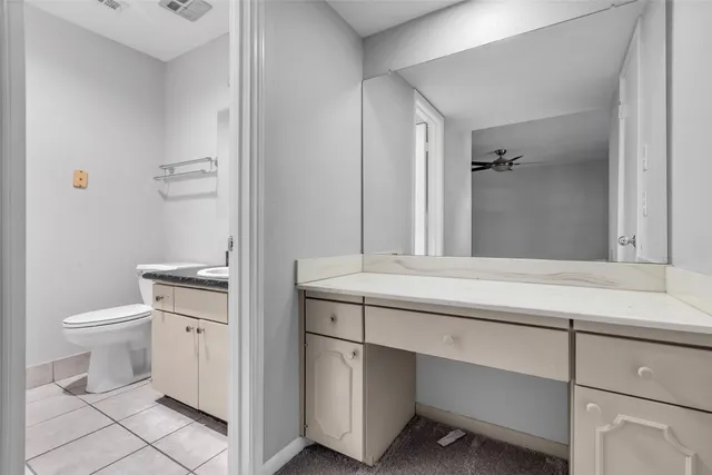 a bathroom with a granite countertop sink a toilet and a mirror