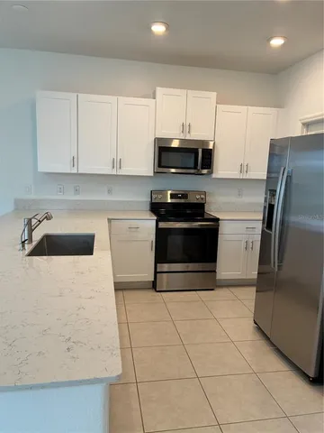 a kitchen with granite countertop a refrigerator sink and white cabinets