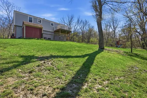 an aerial view of residential house with outdoor space and trees in the background