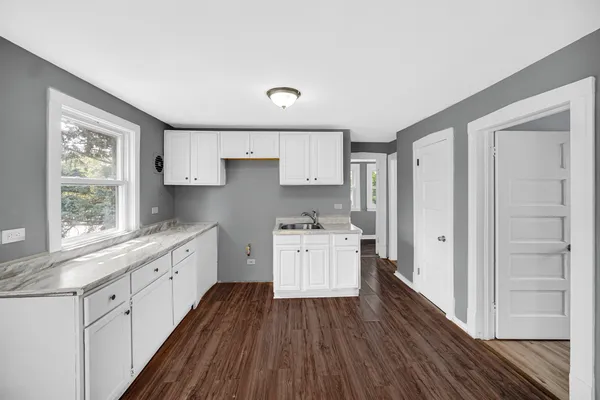 a kitchen with a white cabinets and wooden floor