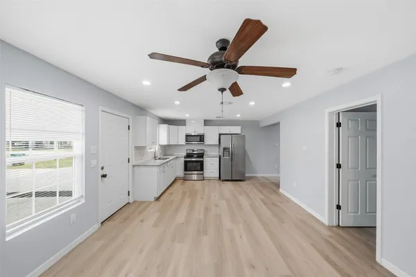 a large kitchen with a lot of white cabinets and stainless steel appliances
