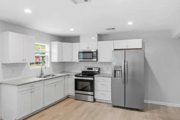 a kitchen with white cabinets stainless steel appliances and a sink