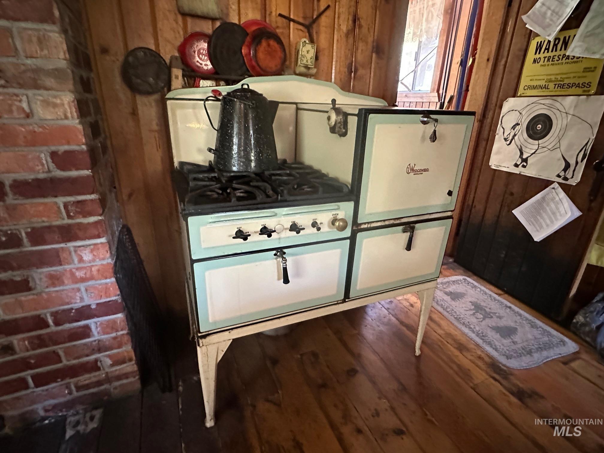 509 Deadline Road, Unit 2 Twin Falls, ID 83301 - Photo 24 of 28 Vintage-style gas range with a four-burner cooktop, integrated oven, and a secondary compartment, set against a backdrop of natural wood paneling and a brick column