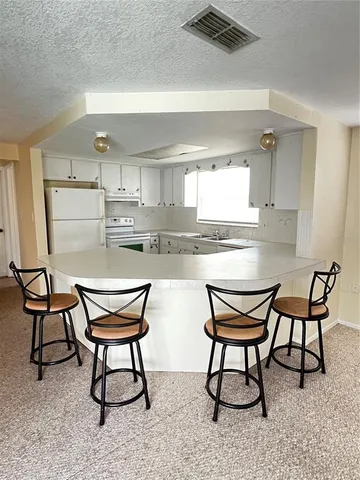 a kitchen with stainless steel appliances kitchen island a table and chair in it