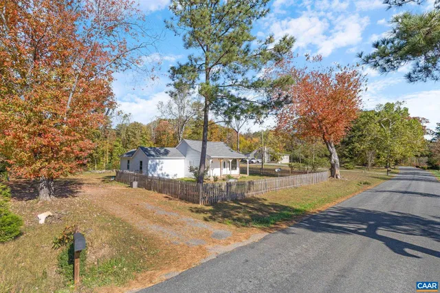 a view of a house with pool and trees in the background