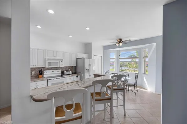 a kitchen with stainless steel appliances granite countertop a table chairs and a refrigerator