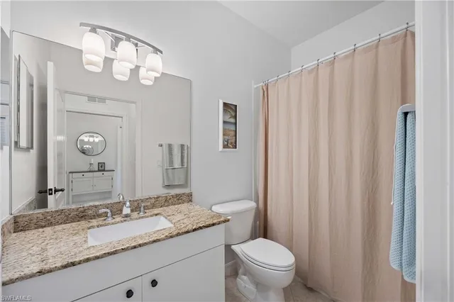 a bathroom with a granite countertop sink a toilet and a mirror