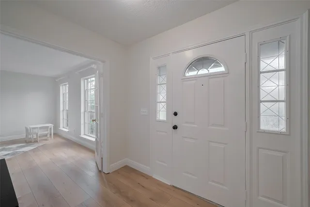 an empty room with wooden floor cabinet and front door