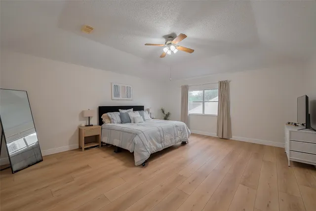 a bedroom with a large bed chandelier and a window