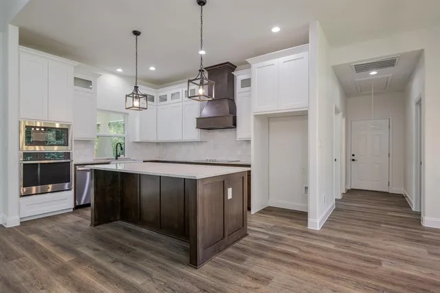 a large kitchen with stainless steel appliances granite countertop a stove a refrigerator and a wooden floors