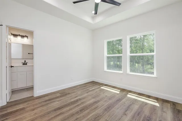 an empty room with wooden floor cabinet and windows