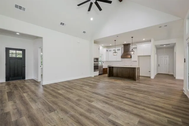 a view of kitchen and empty room with wooden floor