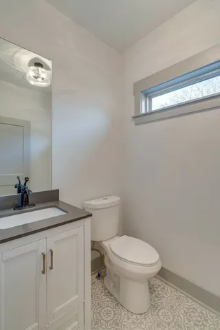 a bathroom with a granite countertop toilet sink and mirror