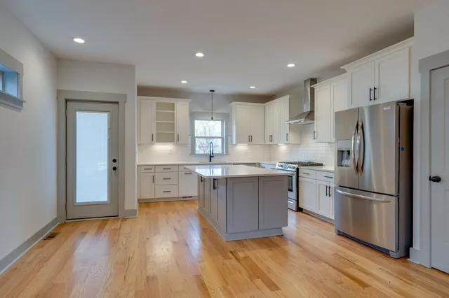 a kitchen with kitchen island wooden floors white appliances and cabinets