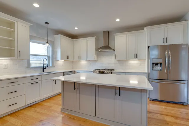 a kitchen with kitchen island white cabinets and refrigerator