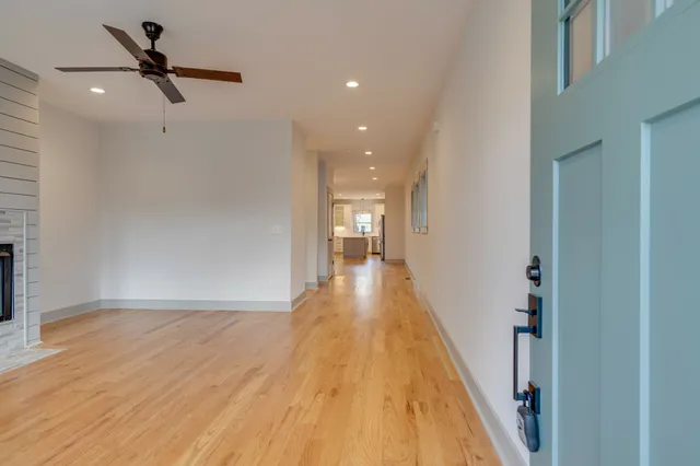 a view of a hallway with wooden floor and a ceiling fan
