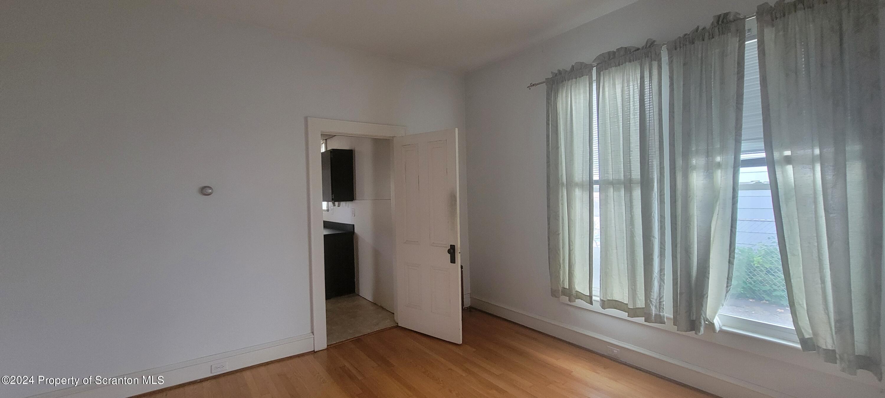 1543 Capouse Avenue Scranton, PA 18509 - Photo 13 of 62 an empty room with wooden floor and a window