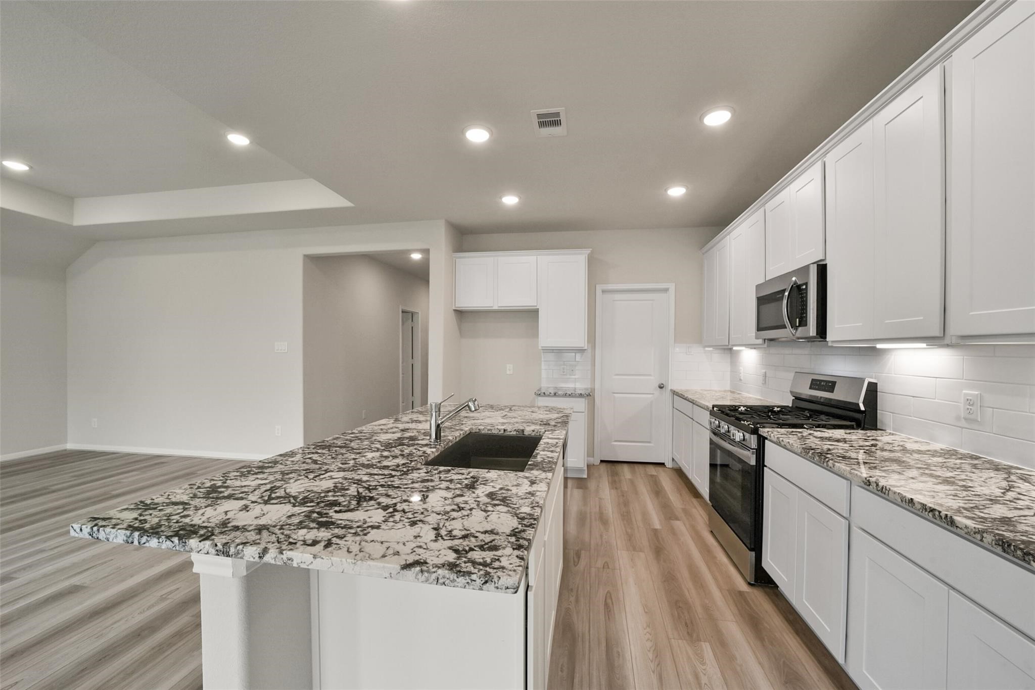10522 Plumas Run Drive Rosharon, TX 77583 - Photo 8 of 29 Bright modern kitchen featuring white cabinetry, granite countertops, and sleek stainless appliances.