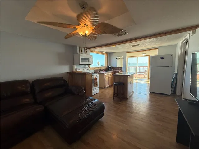 a living room with stainless steel appliances granite countertop furniture and a wooden floor