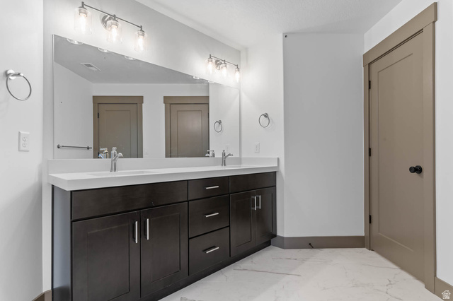 2724 Mt Jordan Road Sandy, UT 84092 - Photo 32 of 33 Bathroom featuring double vanity and light marble finish floors