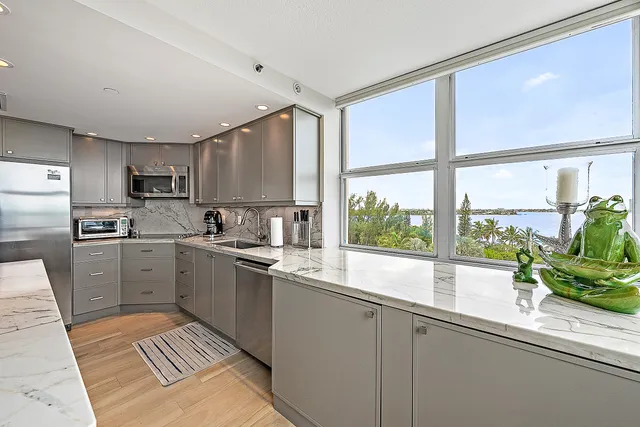 a kitchen with a sink a counter top space stainless steel appliances cabinets and a large window