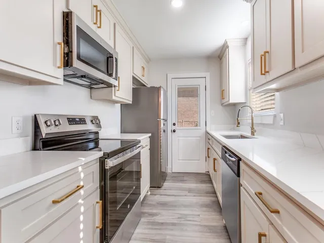 a kitchen with stainless steel appliances a stove microwave and sink