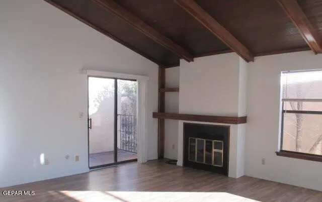 a view of an empty room with wooden floor and a fireplace