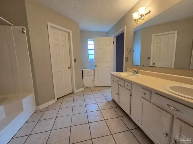 a spacious bathroom with a vanity a mirror and a bathtub