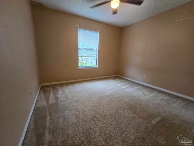 an empty room with a window and a fan