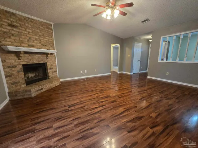 a view of an empty room with wooden floor and a fireplace