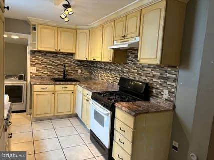a kitchen with granite countertop a stove sink and cabinets