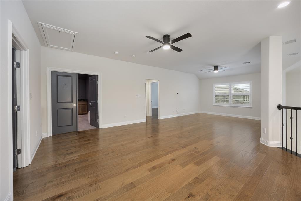 918 Sydney Lane Allen, TX 75013 - Photo 23 of 40 Expansive room featuring hardwood floors, white walls, and two ceiling fans