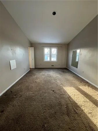 an empty room with windows and fireplace