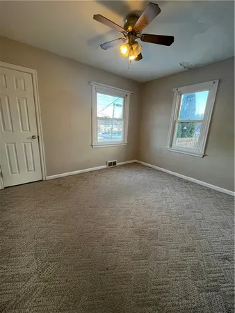 an empty room with windows and fan
