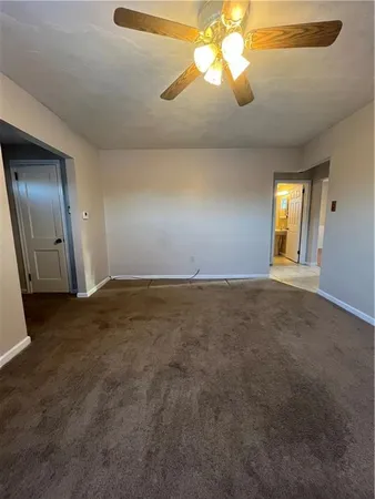 a view of an empty room and chandelier fan