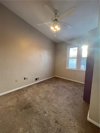 en empty room with windows and ceiling fan