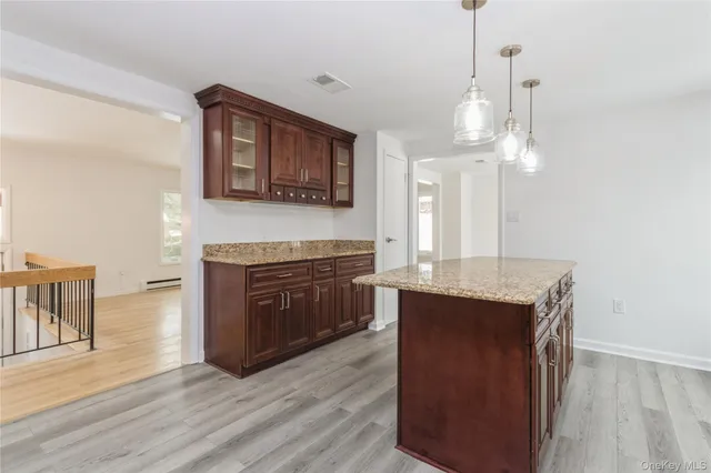 a living room with stainless steel appliances granite countertop couches a fireplace and a flat screen tv