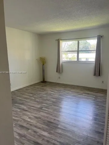 a view of an empty room with closet and wooden floor