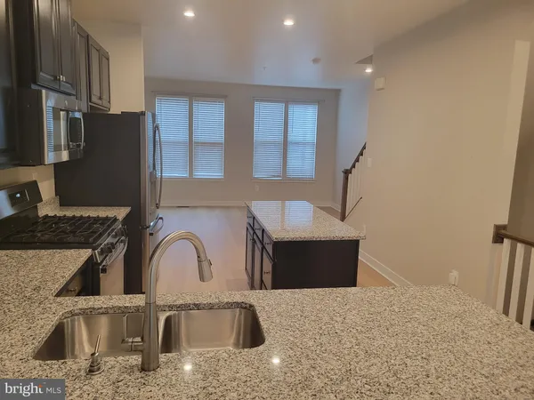 a kitchen with stainless steel appliances granite countertop a sink a stove and a refrigerator