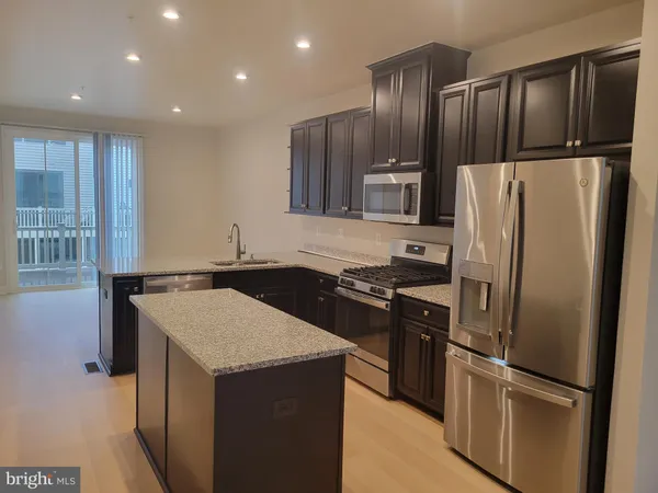 a kitchen with granite countertop a refrigerator and a stove top oven
