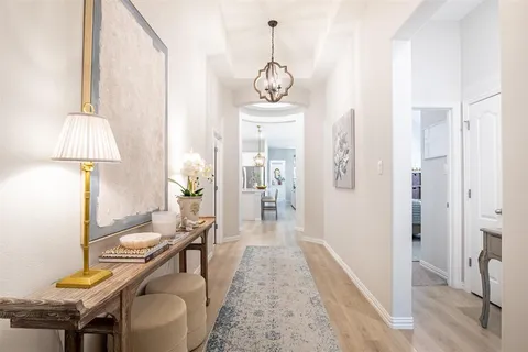 a view of a hallway with furniture and chandelier