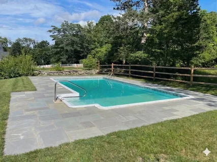 a view of backyard with swimming pool and seating space