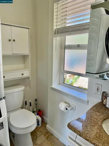 a bathroom with a granite countertop sink and a toilet