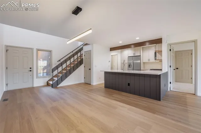 a view of an empty room with wooden floor and stairs