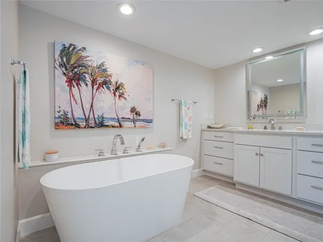 a bathroom with a double vanity sink mirror and bathtub