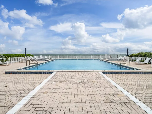 a view of swimming pool with outdoor seating and lake in the back
