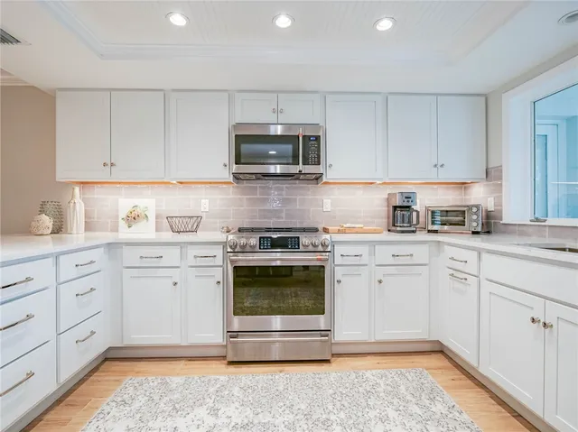 a kitchen with granite countertop white cabinets and stainless steel appliances